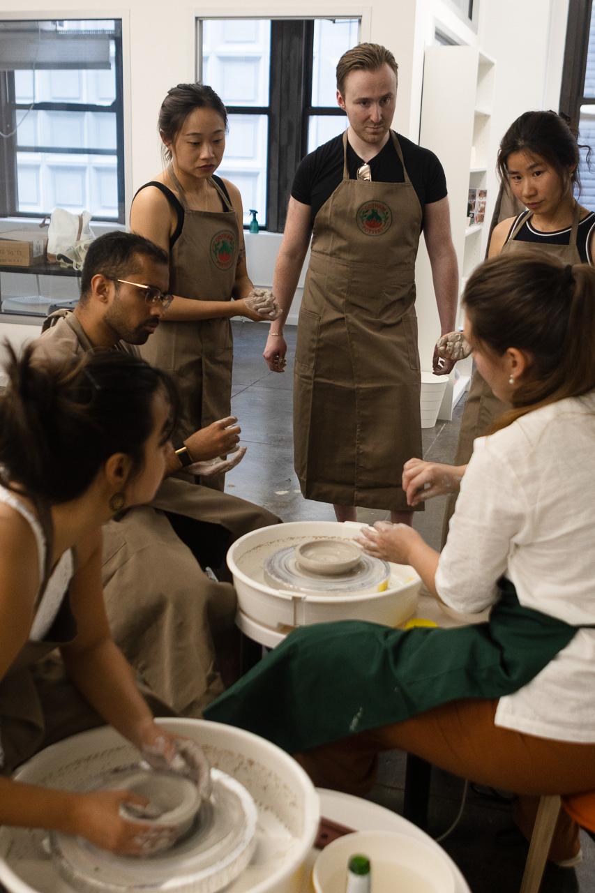 Students learning wheel throwing in a Gotham Pottery course